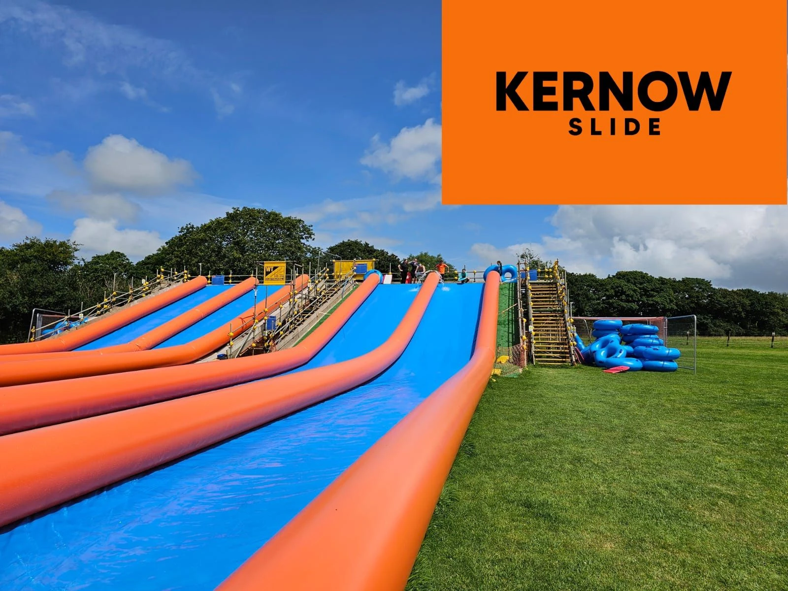 A group of adults riding inflatable rings at Kernow Slide
